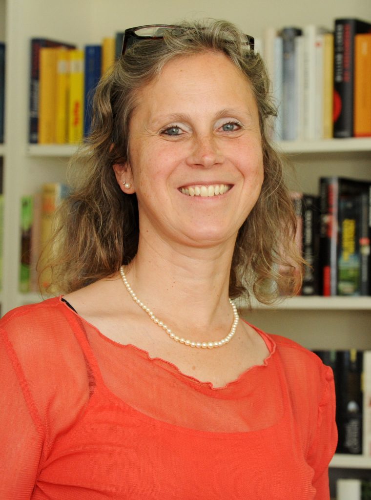 Profilbild einer Frau, im Hintergrund Bücherregale